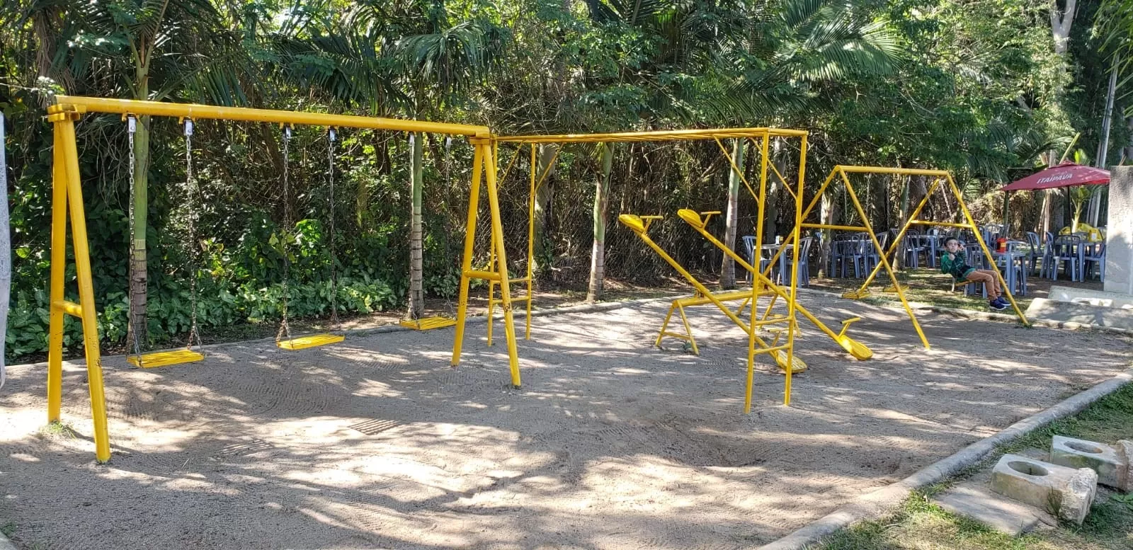 Área infantil do Pesqueiro do Louro, com brinquedos pintados na cor amarela em cima de uma caixa de areia.