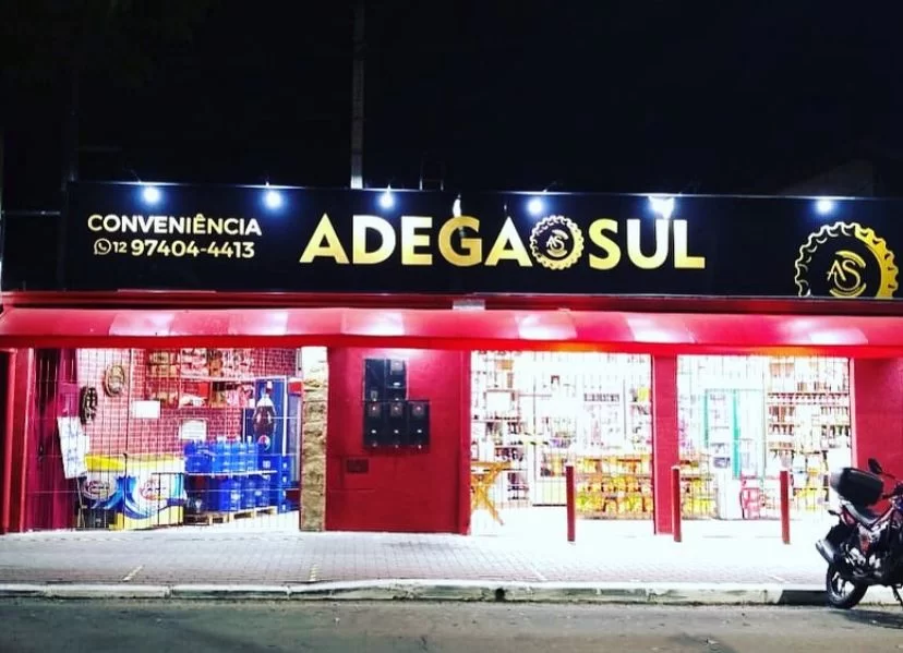 Adega Sul é outra opção em São José dos Campos; foto mostra céu preto durante uma noite, fachada da empresa com letras em amarelo e parede vermelha.