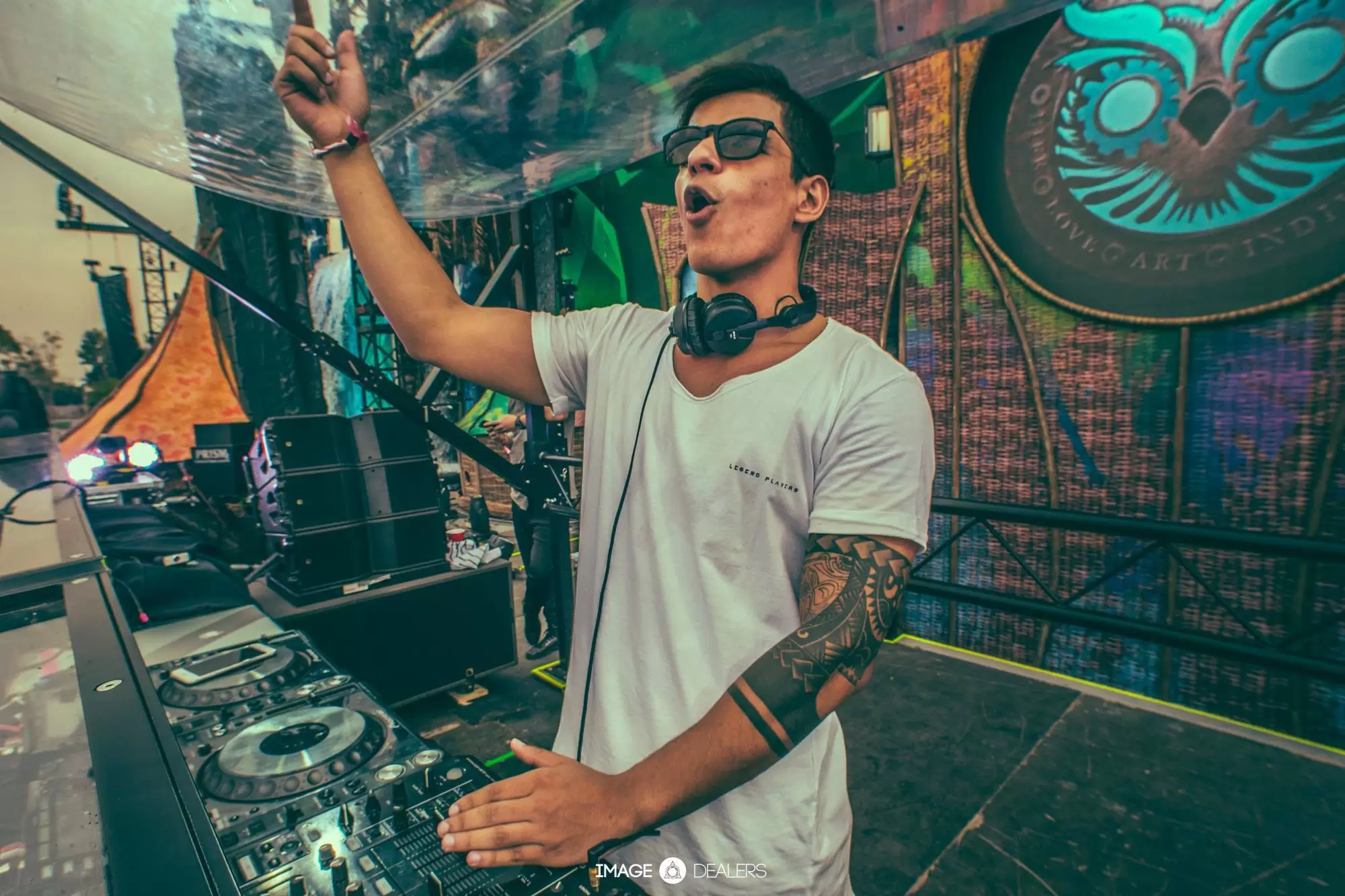 Foto ilustra matéria sobre show do DJ Vintage Culture em São José dos Campos (SJC), no Palácio Sunset. Na imagem, o artista usa camiseta branca, fones de ouvido, óculos preto e está com um dos braços para cima.