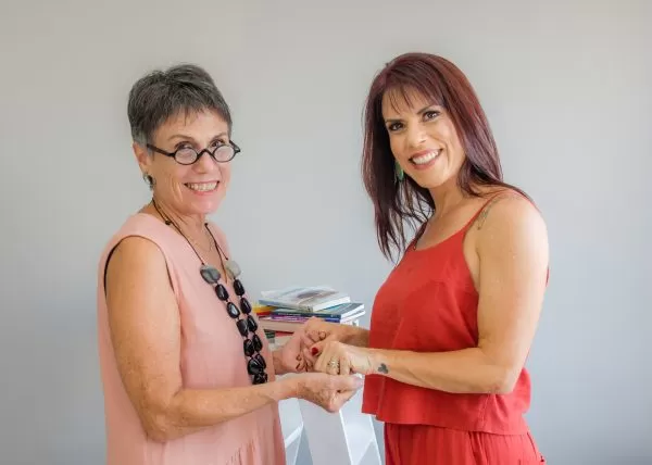May Parreia (à esquerda) e Tati Iaconelli (à direita), em frente a um fundo cinza; foto ilustra matéria sobre reestreia da coluna Ofício das Palavras.