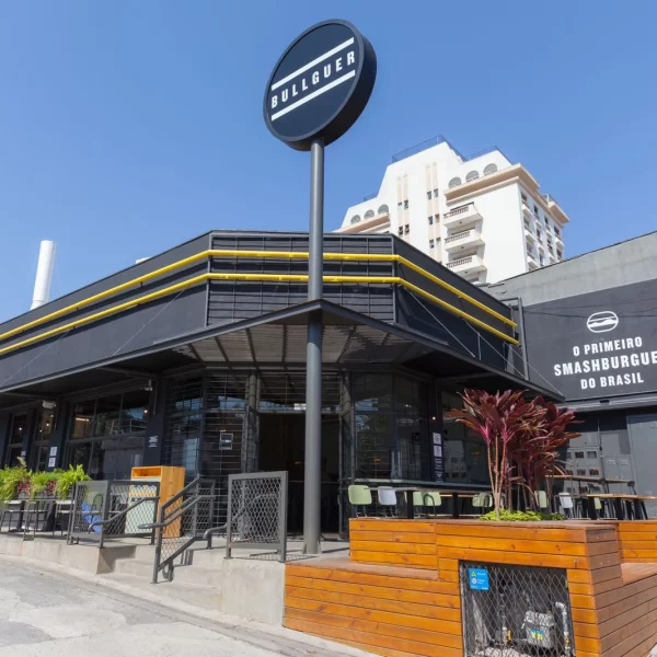 Fachada do Bullguer, no Jardim Aquarius, com um céu azul ao fundo e construção em preto, amarelo e detalhes em madeira; foto ilustra matéria sobre hamburguer artesanal em SJC.