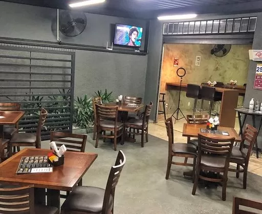 Parte interna do Burguin, no Jardim das Indústrias, em São José dos Campos, com parede cinza, TV pendurada, mesas de madeira e um teto preto.