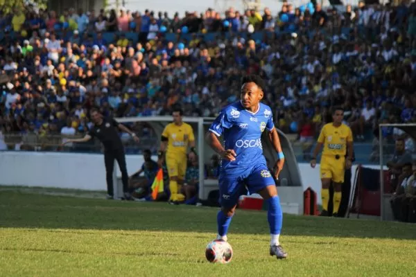 Jogador do São José EC com uniforme azul, durante primeiro jogo da final do Campeonato Paulista A3, contra o Capivariano, com estádio lotado.