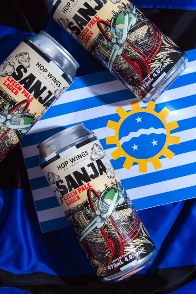 latinhas da cerveja sanja sobre pano azul e imagem da bendeira de são josé dos campos, sjc