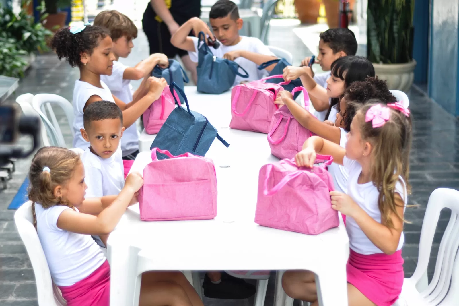 crianças em hora da refeição na escola com lancheiras sobre a mesa