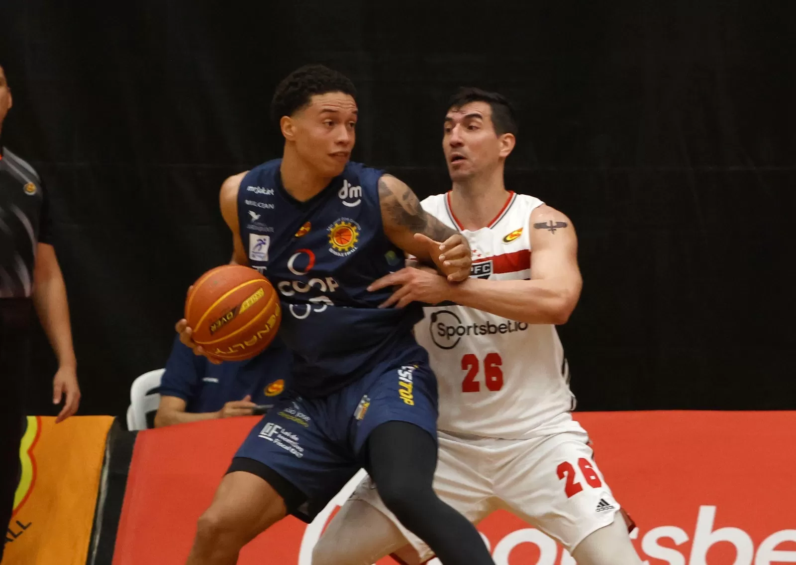 Jogador do São José Basketball com a bola, sendo marcado por atleta do São Paulo, na estreia do Campeonato Paulista