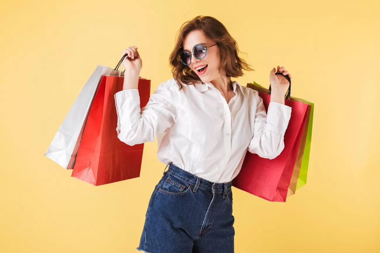 Mulher usando óculos, em pé, com sacolas de compras. Outlet em sjc pode ser uma boa opção para fazer compras