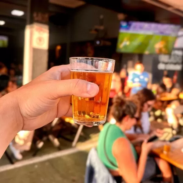 homem segurando copo de cerveja no espetinho do papai