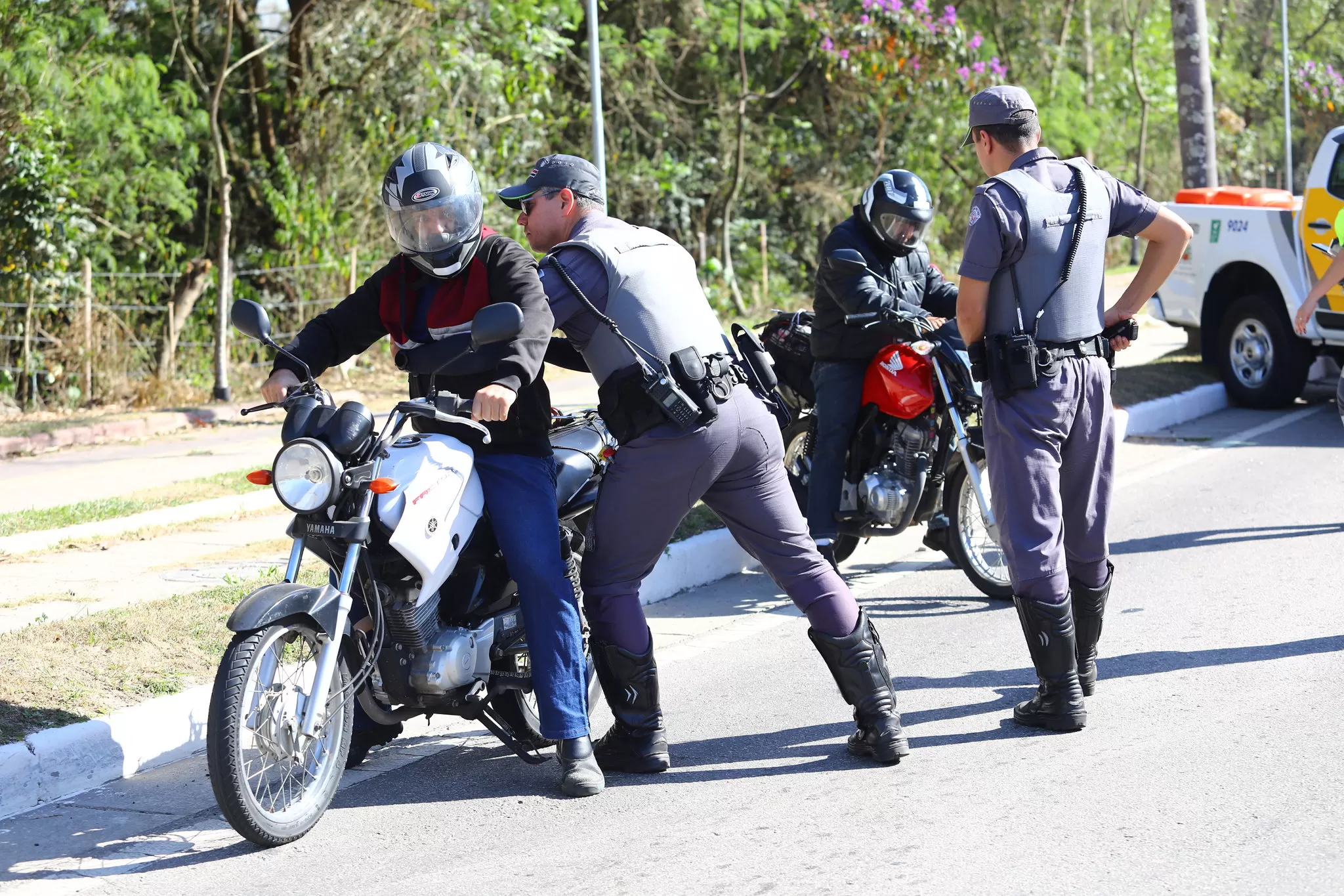 policiais em operação para fiscalização de transporte clandestino em são josé dos campos; oficial aparece ao lado de motociclista em cima de moto durante aboragem