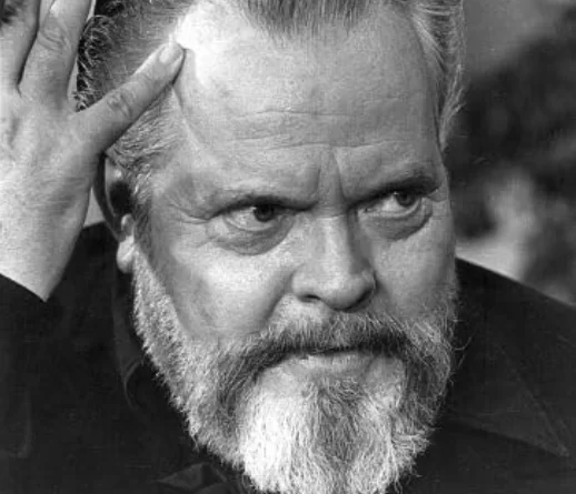 orson welles, de barba e em preto e branco, sério e com a mão direita na parte lateral do rosto