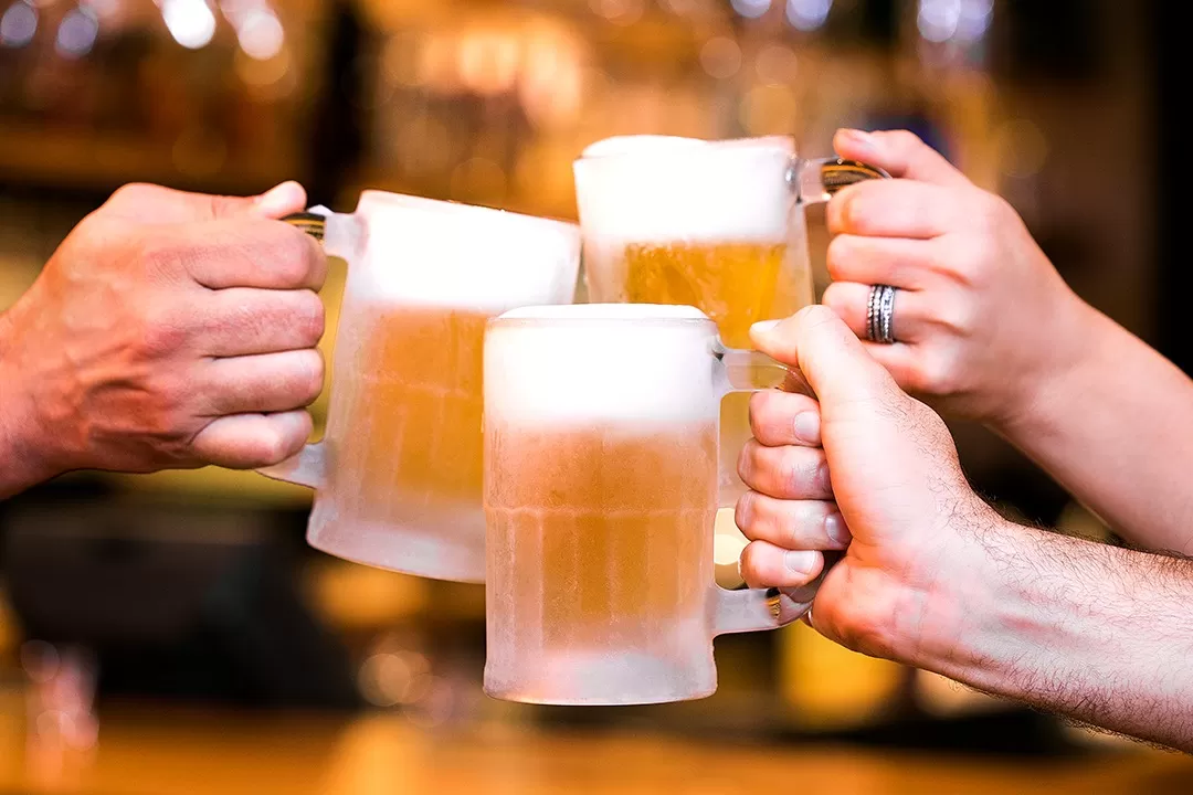 mãos brindando com canecões de chopp do outback