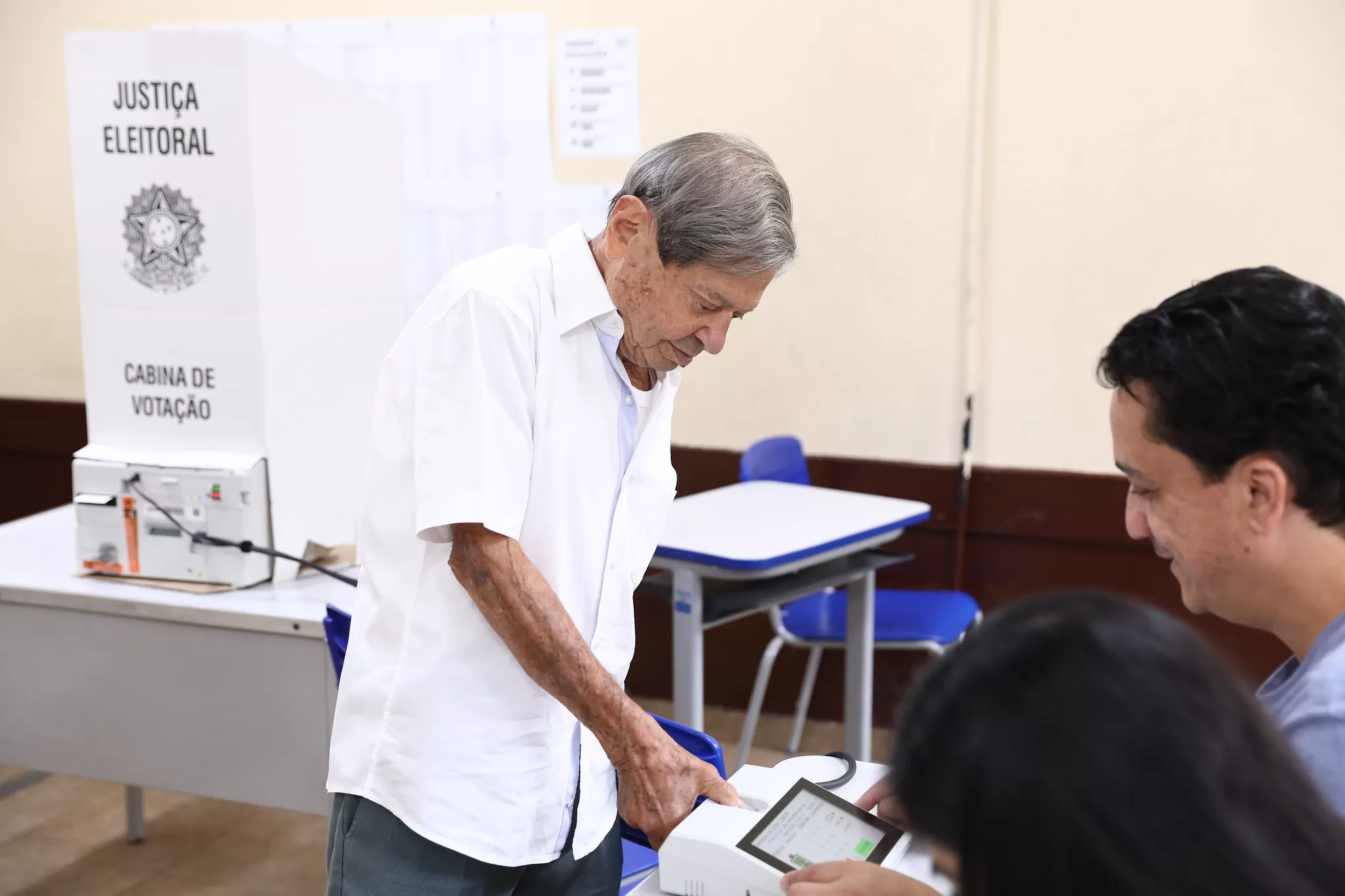 homem fazendo biometria em máquina antes de votar em cabine de votação nas eleições