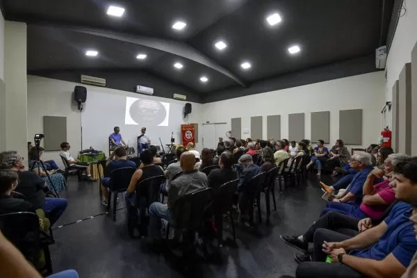 casa cheia na cia bola de meia em sjc, com cadeiras enfileiradas em frente ao palco em que poeta moraes recita seus versos