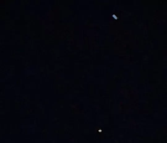 OVNI azul acima acompanhado pela luz brilhante no céu durante a noite