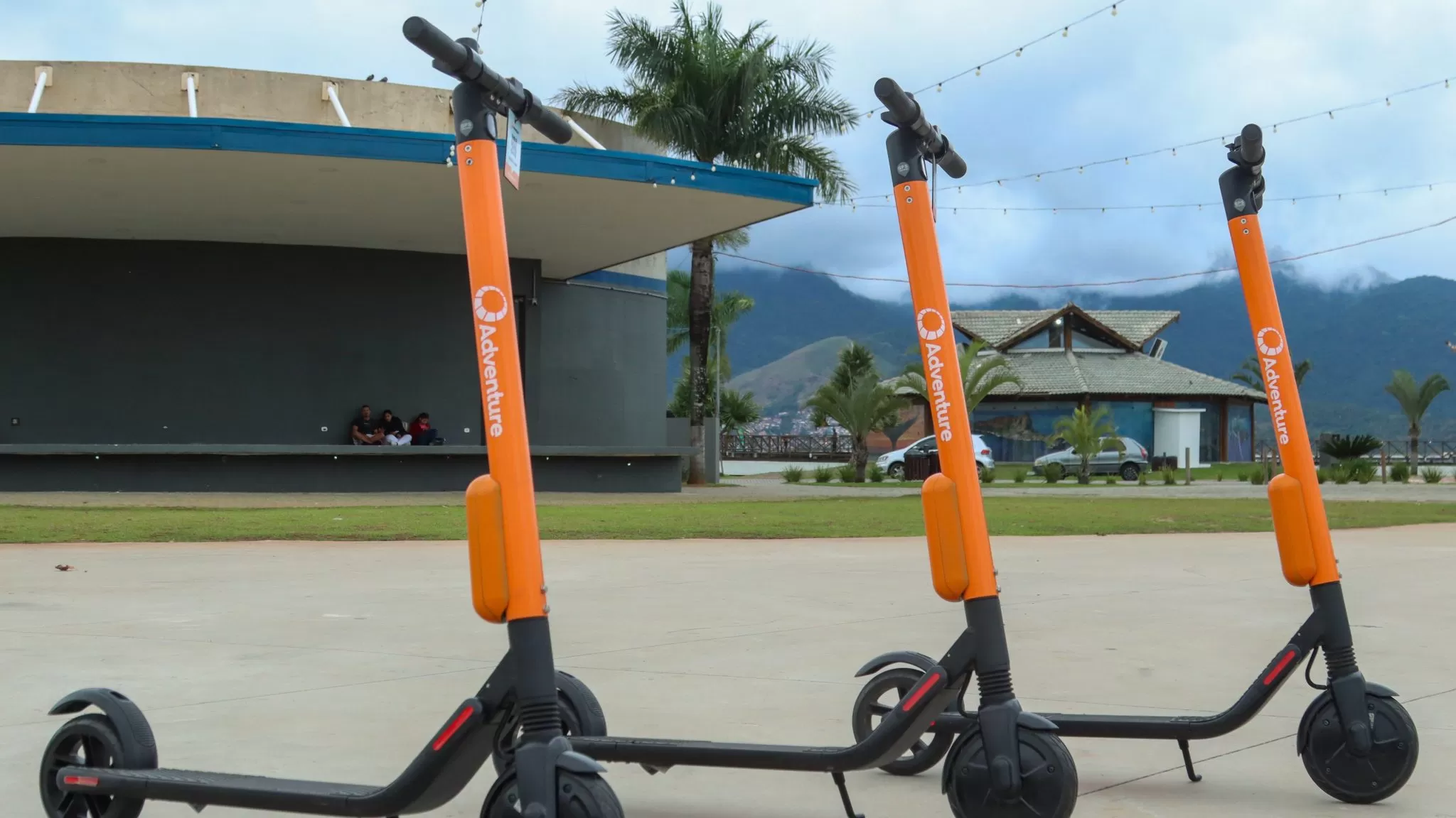Patinetes elétricos laranja da Adventure estacionados em São Sebastião